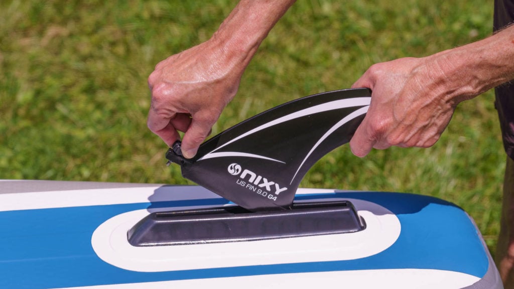 Inserting the single large US Fin Box screw-in fin into the bottom of the SUP